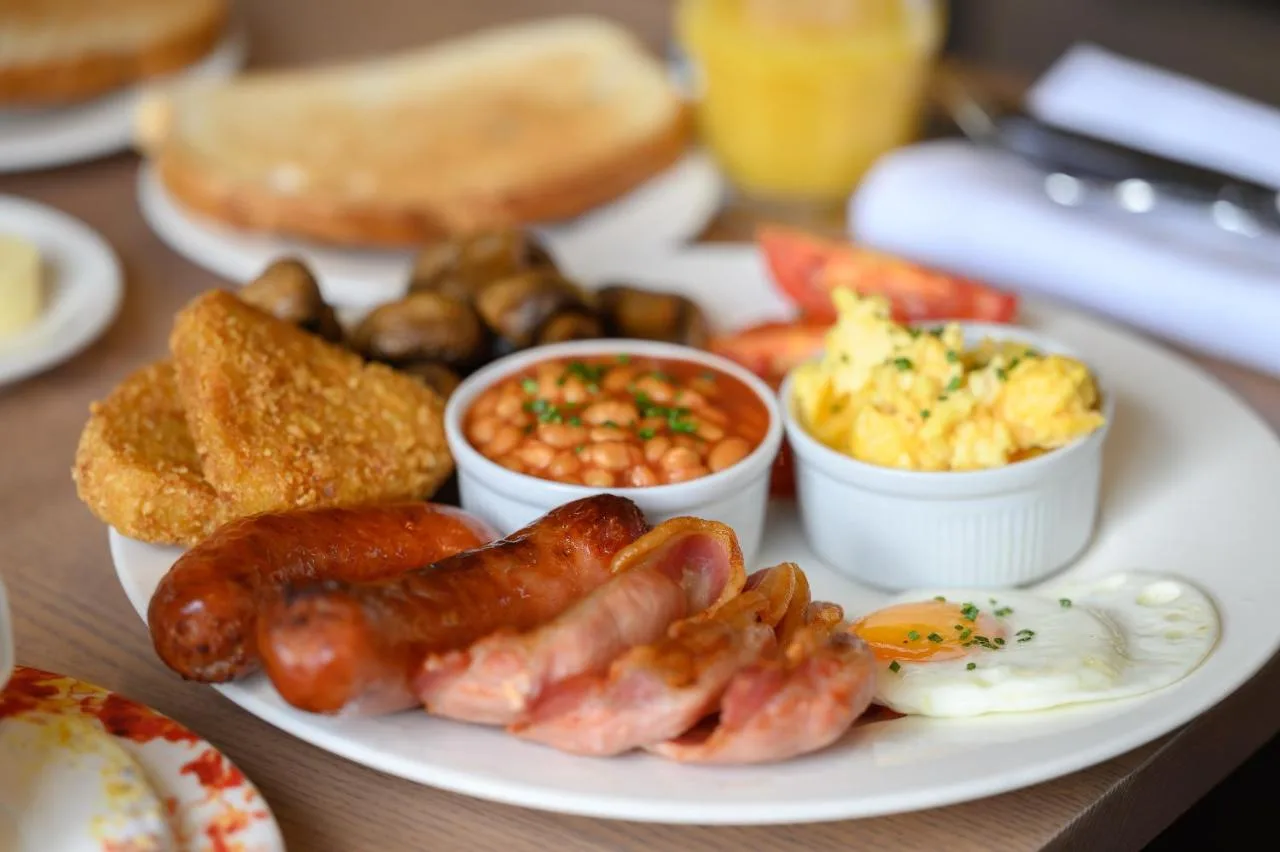 a plate of breakfast food with sausage eggs bread and beans at Edgbaston Park Hotel Birmingham in Birmingham